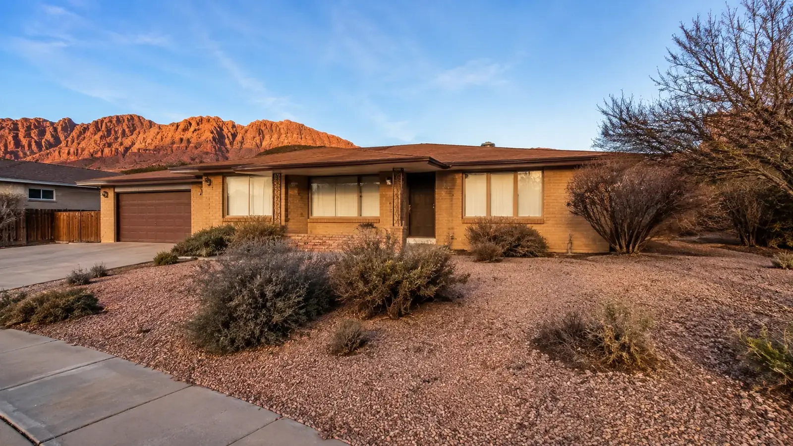 Older single story home in St. George, Utah, with closed curtains, gravel landscaping and untended shrubs